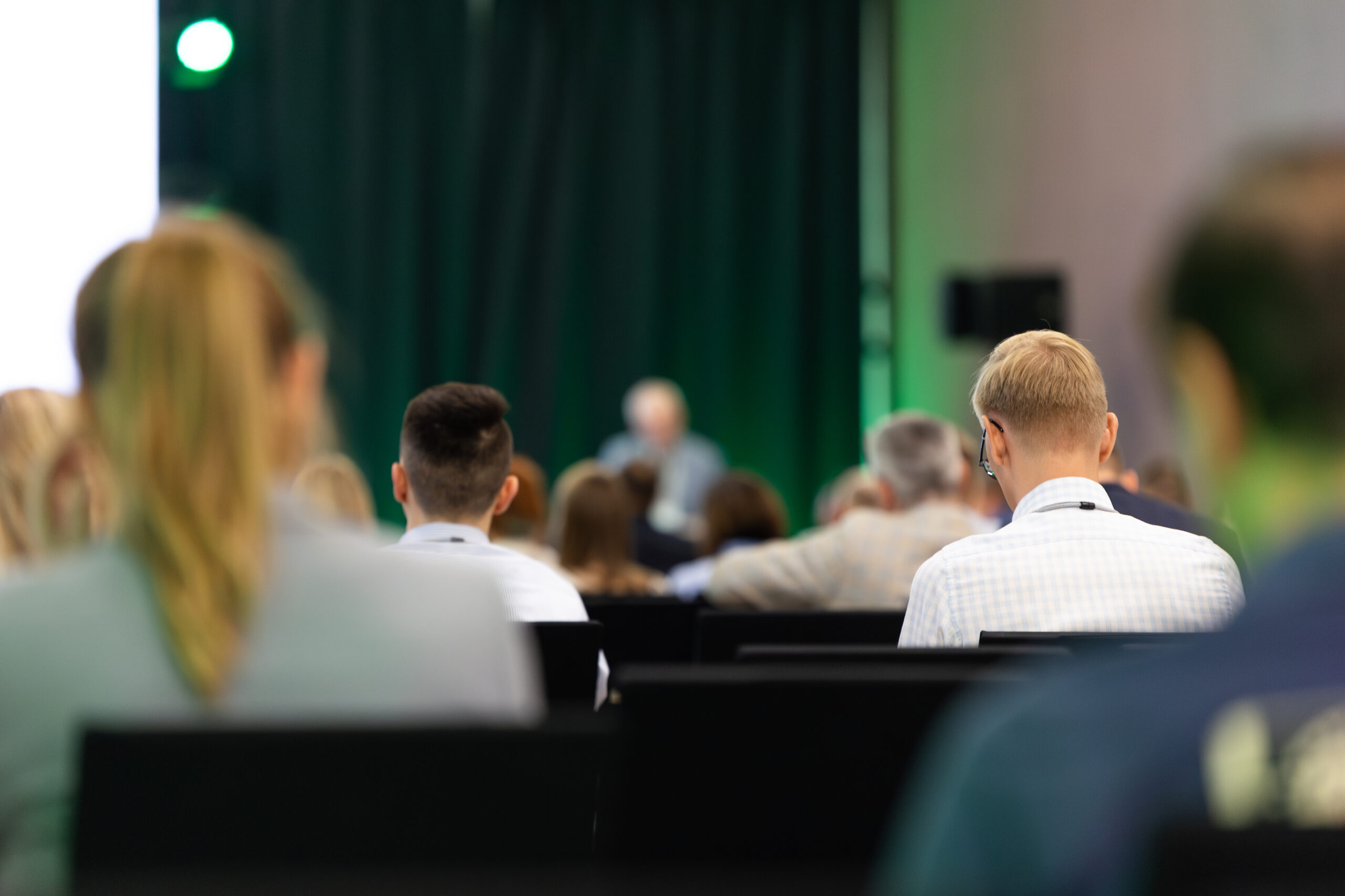 Rear view of the audience at a business conference meeting event listening to the speakers speech